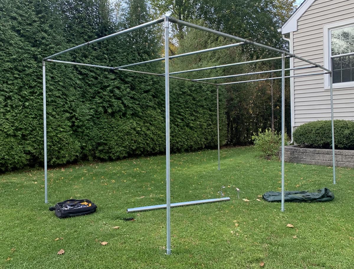 Metal sukkah frame partially assembled on a lawn