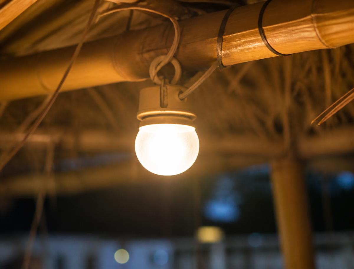 Warm light fixture hanging from a bamboo sukkah beam at night